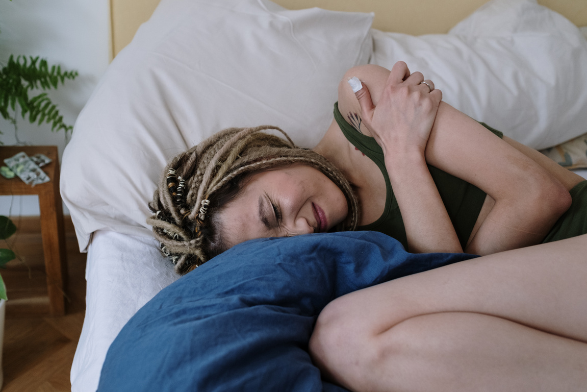 Woman Suffering from a Stomach Pain Lying Down on Bed